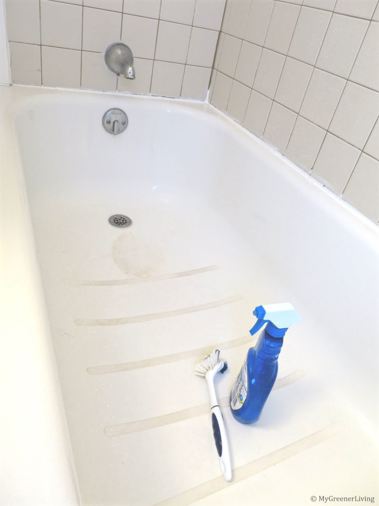tub with vinegar + Dawn shower cleaner in a spray bottle next to a cleaning brush