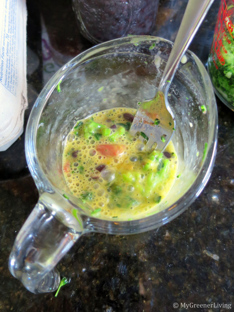 egg and veggies mixed in a measuring cup before being poured into mason jars for baking