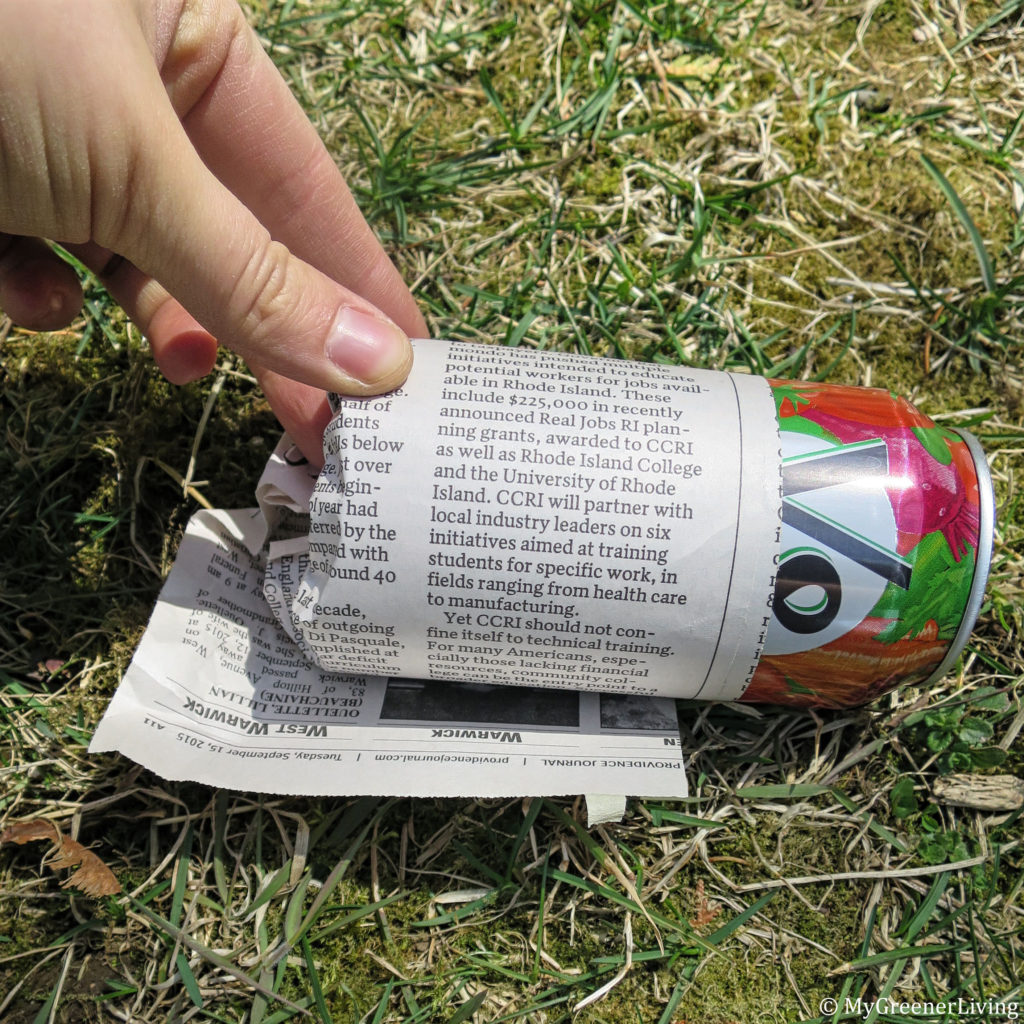 rolling newspaper around can to create a seed starter container